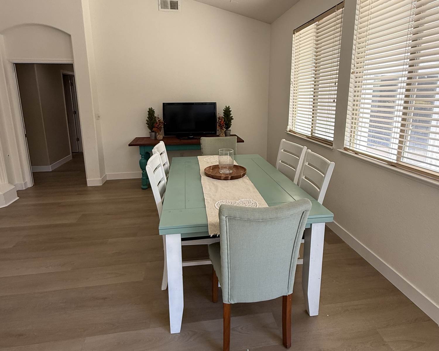 Dining room with a teal farmhouse table and big windows