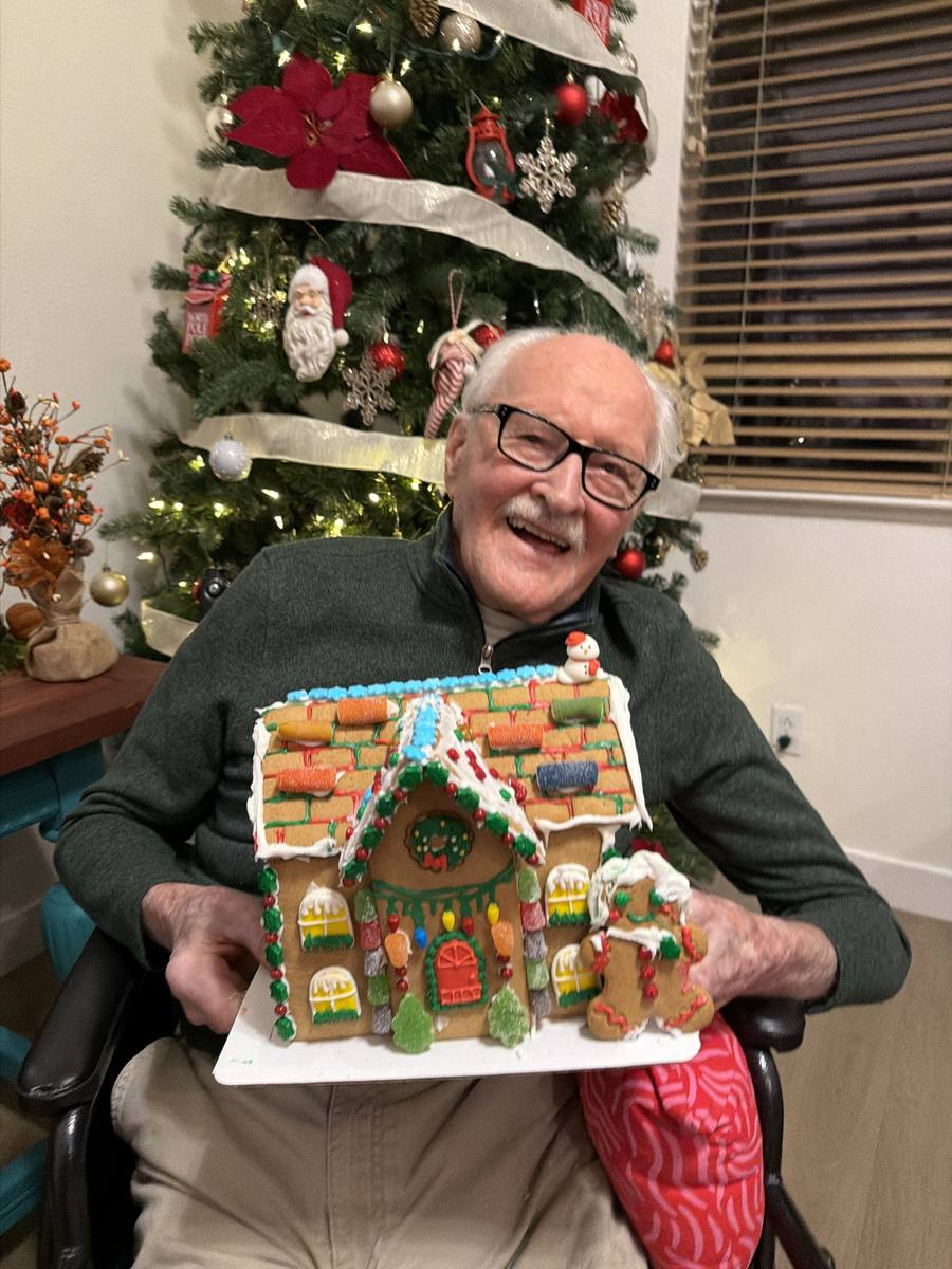 A resident laughing while holding the gingerbread house he decorated