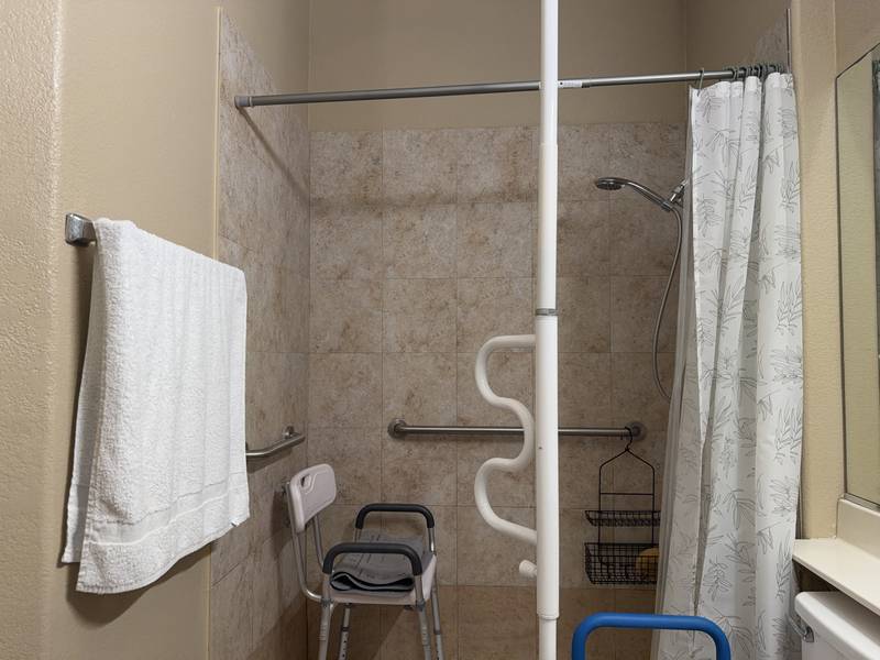 Walk-in shower with grab bars and a shower chair